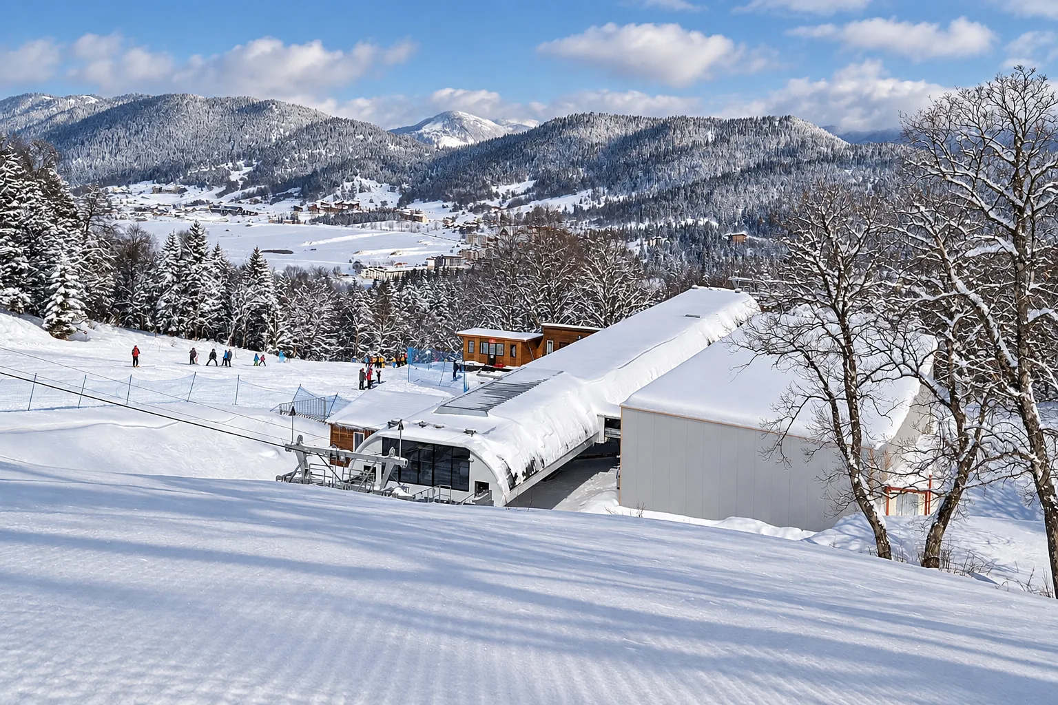 Snow-covered lower lift station at Kokhta above Bakuriani with skiers on the piste and the town in the forested valley below