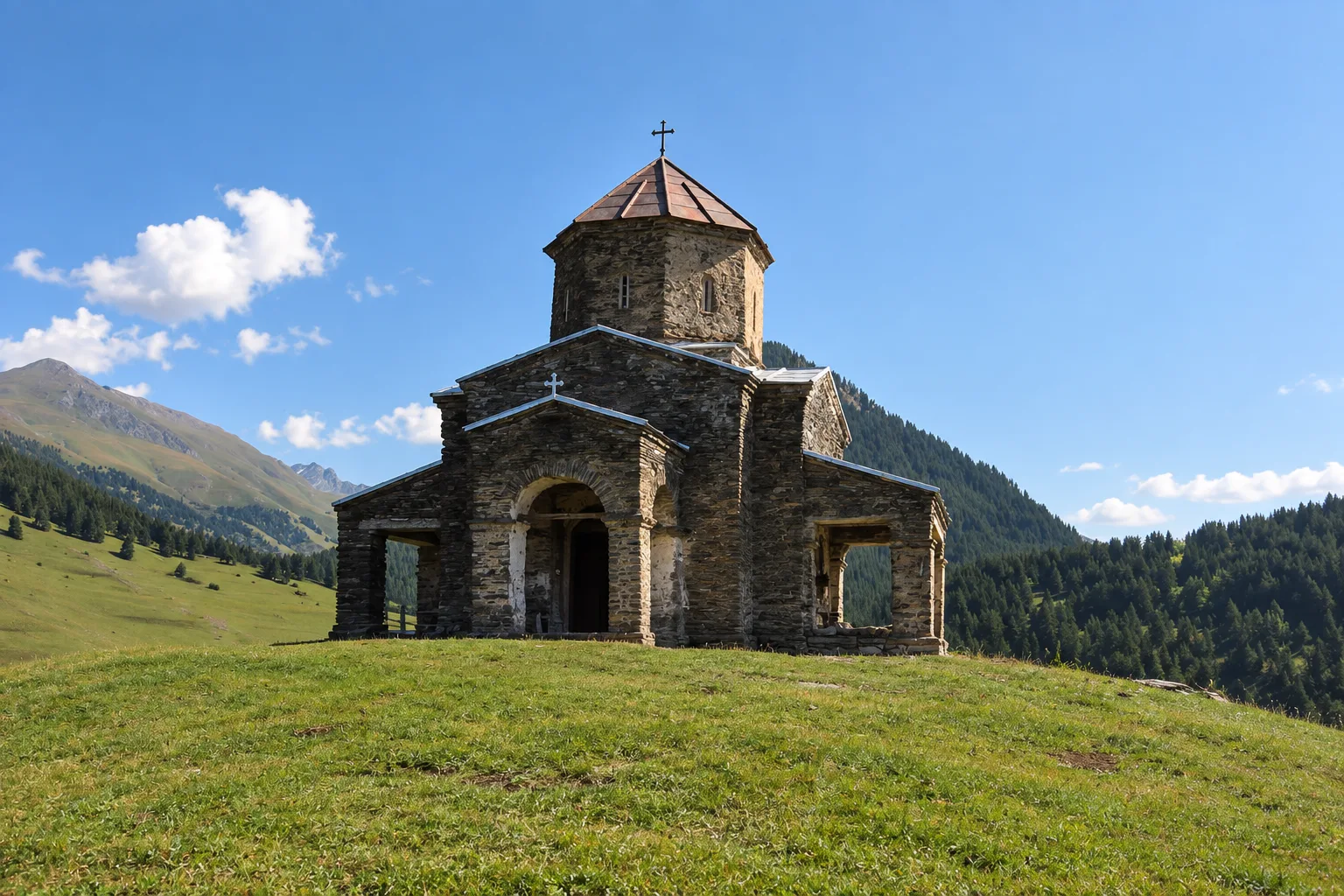 The small slate-stone church of Shenako with its octagonal drum and pyramid roof on a grassy knoll, forested slopes and a green ridge behind under a clear sky