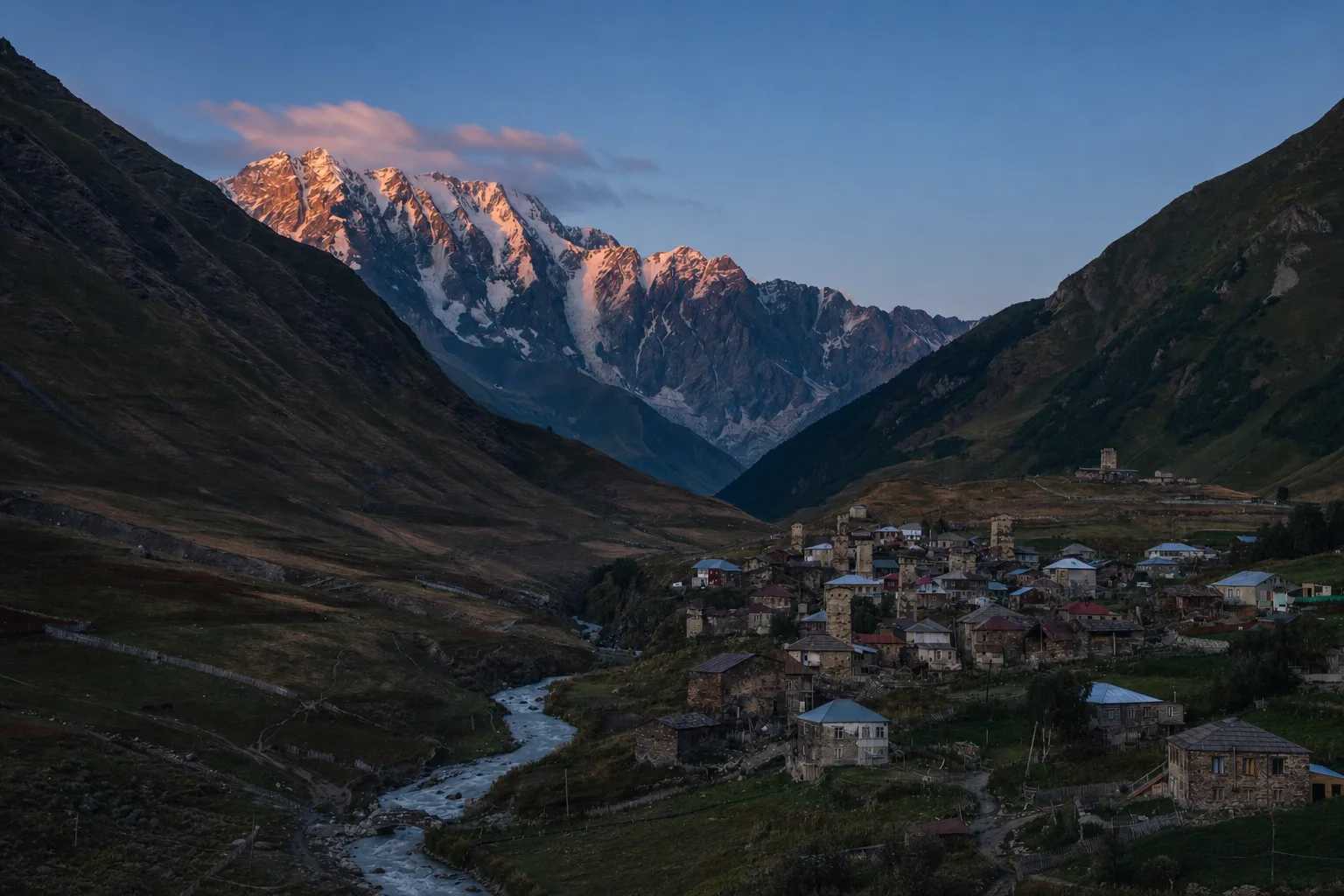 Ushguli's towers and houses at dusk with the last light on the snow of Shkhara at the head of the valley