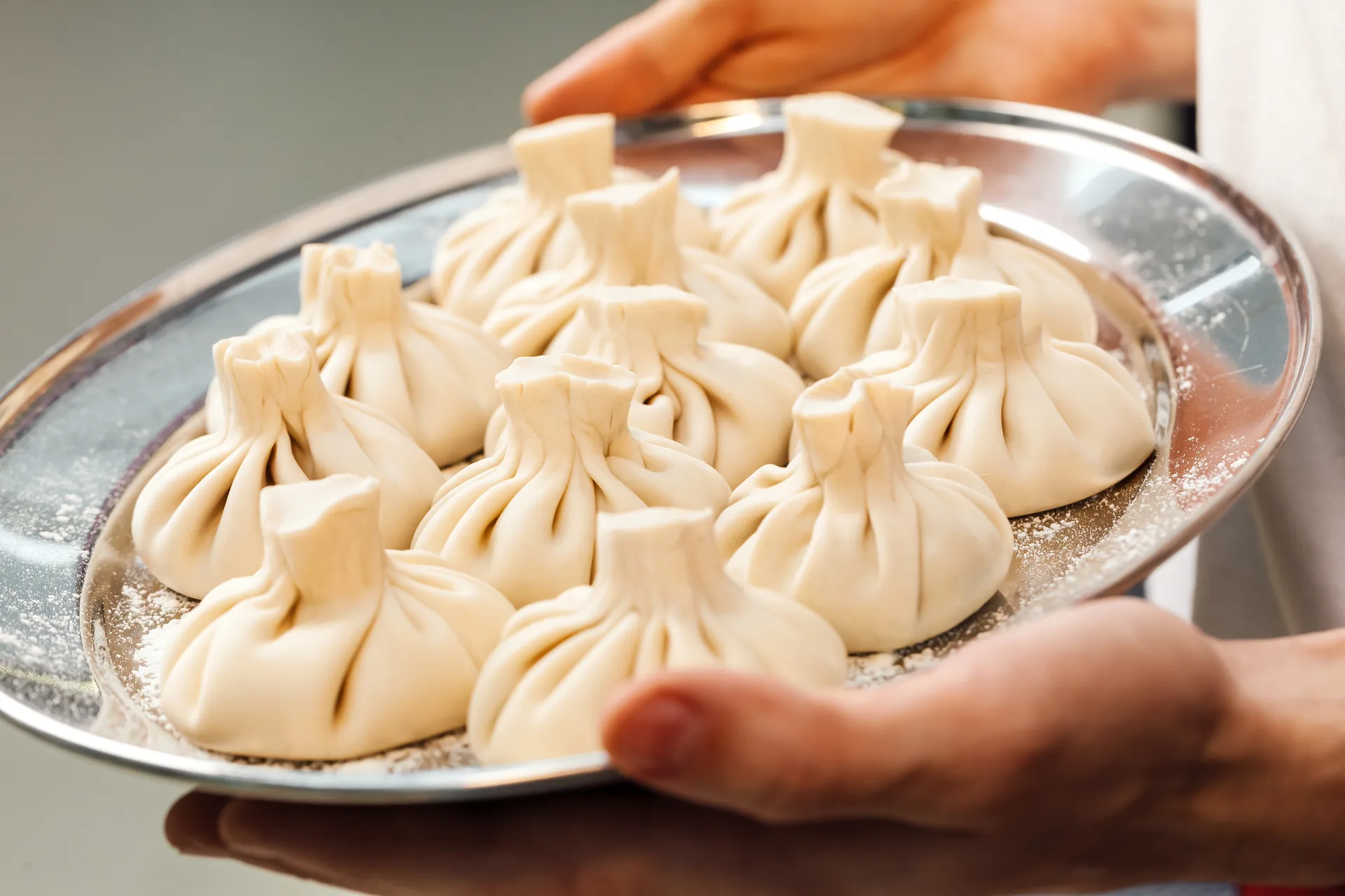 Close-up of freshly made Georgian khinkali dumplings being held on a tray