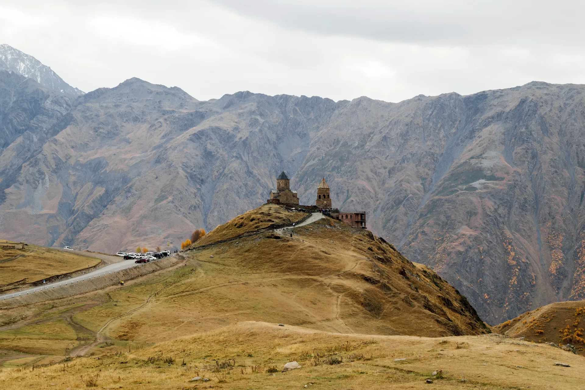 Gergeti Trinity Church in autumn with colorful foliage and the Caucasus mountains