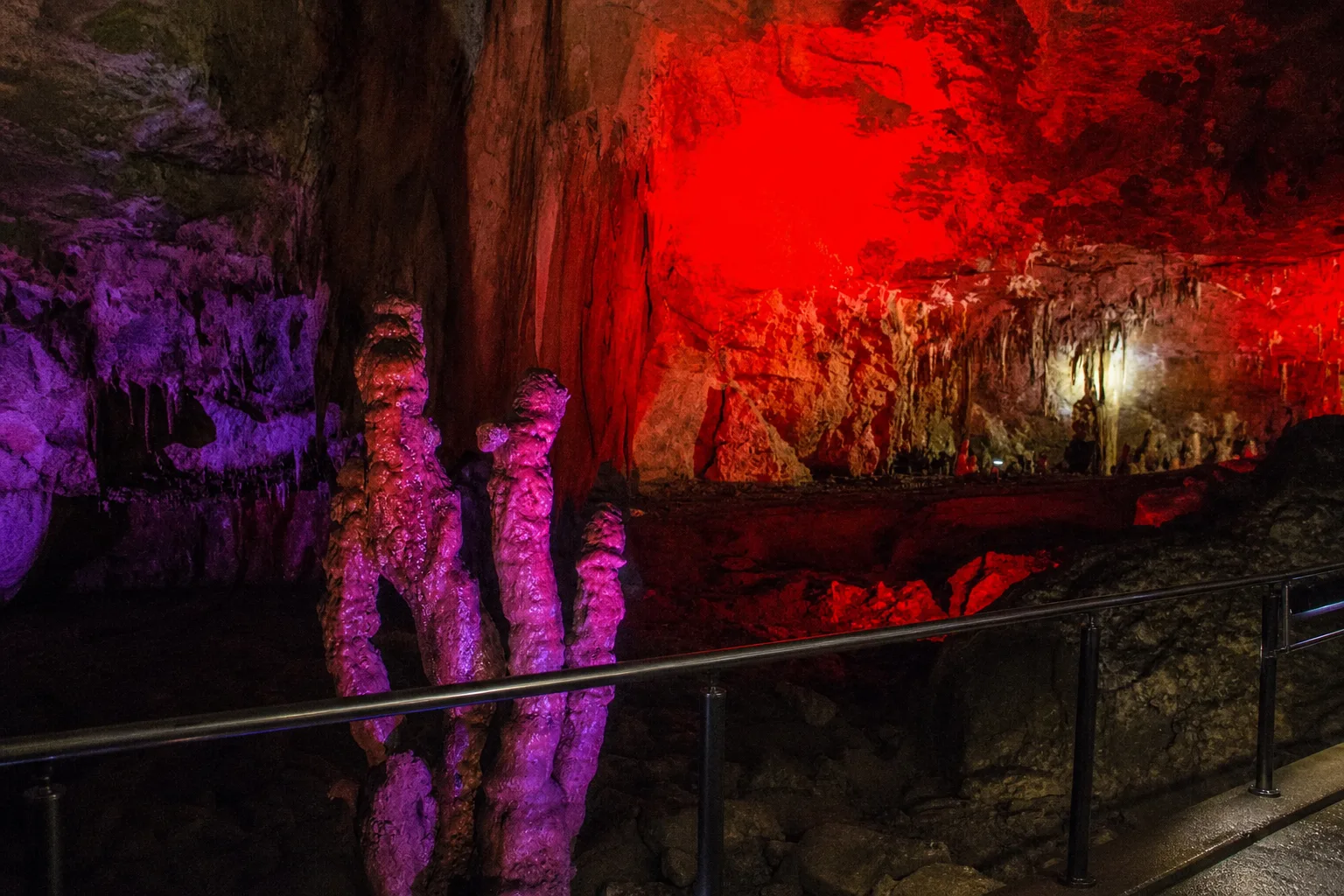 Coloured floodlights on tall stalagmites inside Prometheus Cave near Kutaisi, seen from the visitor walkway