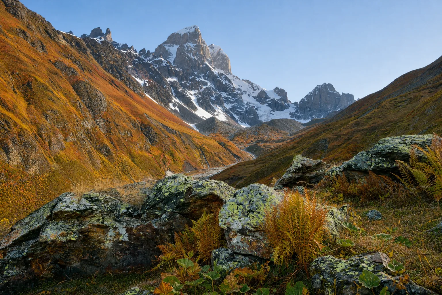The twin peaks of Mount Ushba above a wide Svaneti valley in mid October, with autumn colour on the lower slopes under a clear sky