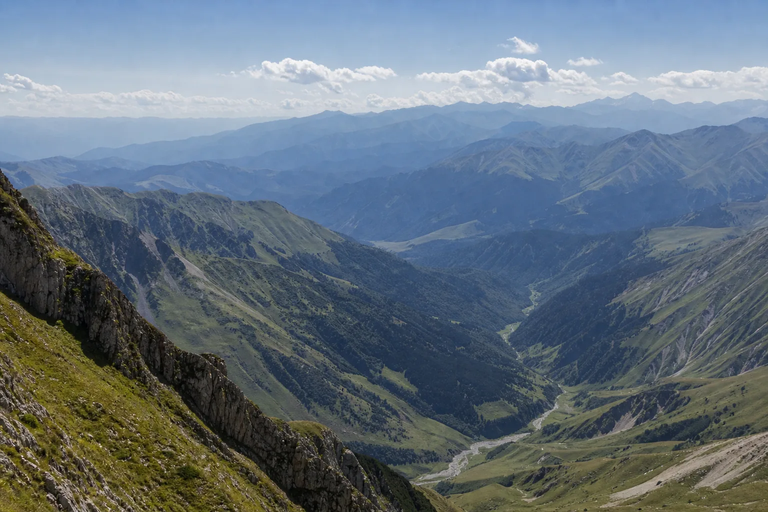 Layered Caucasus ridges fading into haze above a deep valley near Gudauri