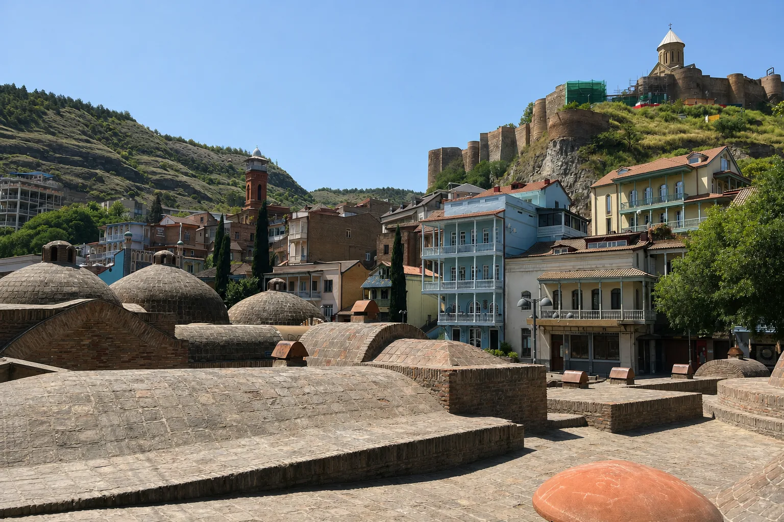 The brick domes of the Abanotubani sulfur bathhouses with Narikala on the ridge behind
