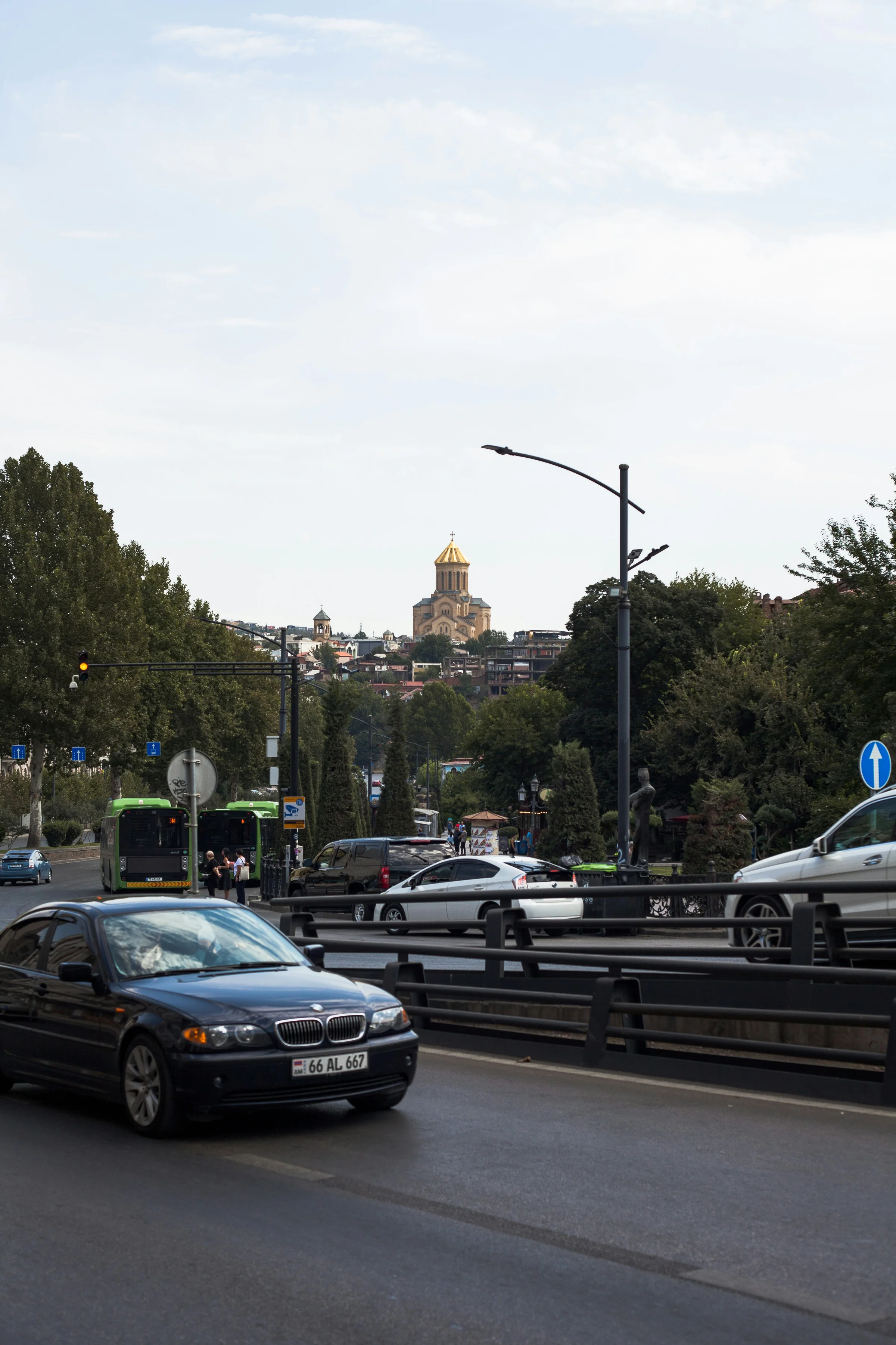 A car driving through Tbilisi with the Holy Trinity Cathedral in the background