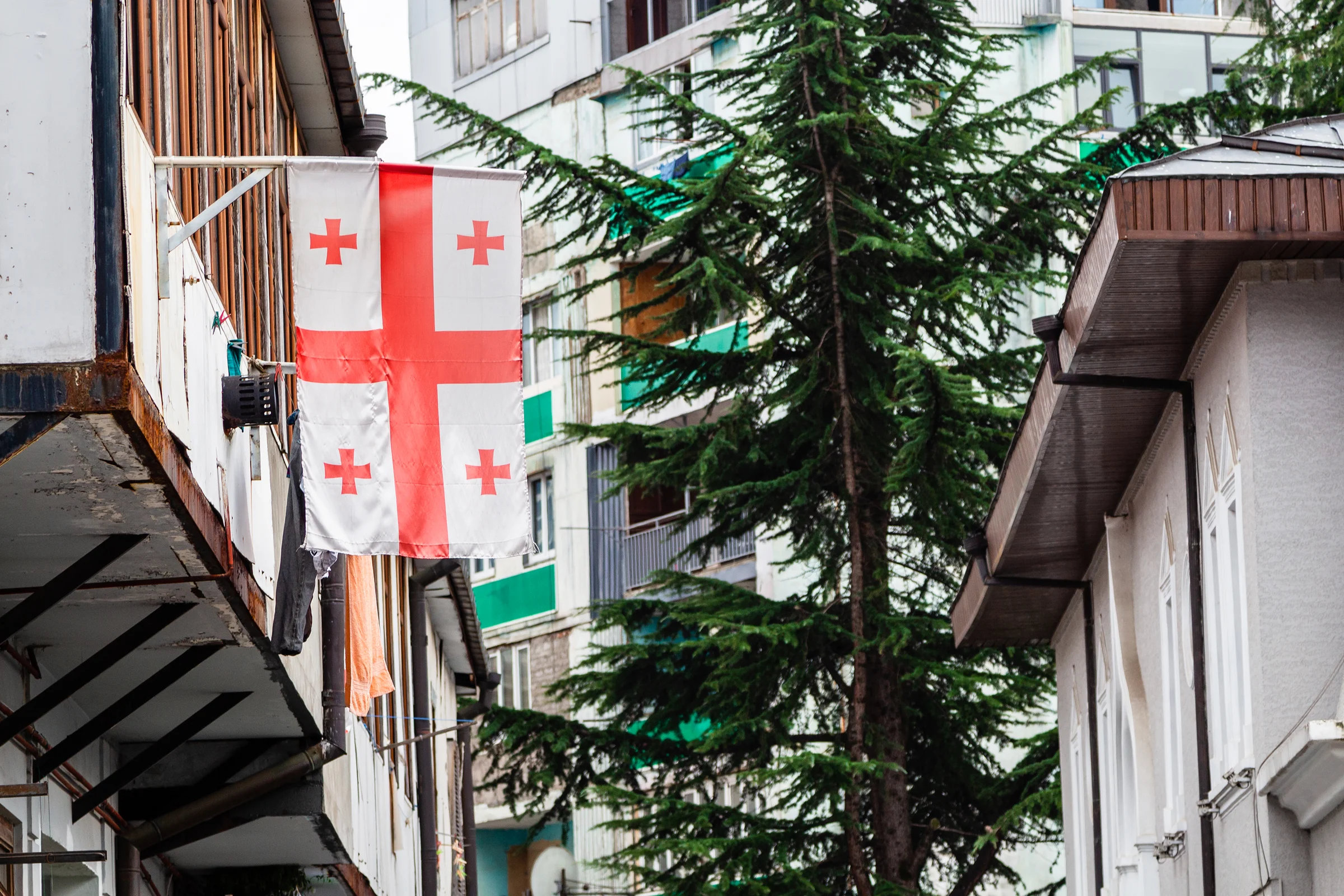 Georgian flag hanging from a traditional residential balcony in Tbilisi