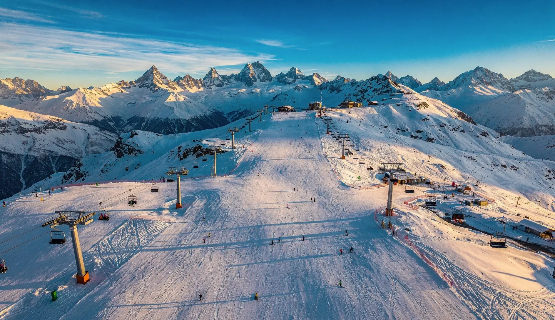 Panoramic view of Gudauri ski resort with snow-covered slopes and the Greater Caucasus mountains in golden morning light