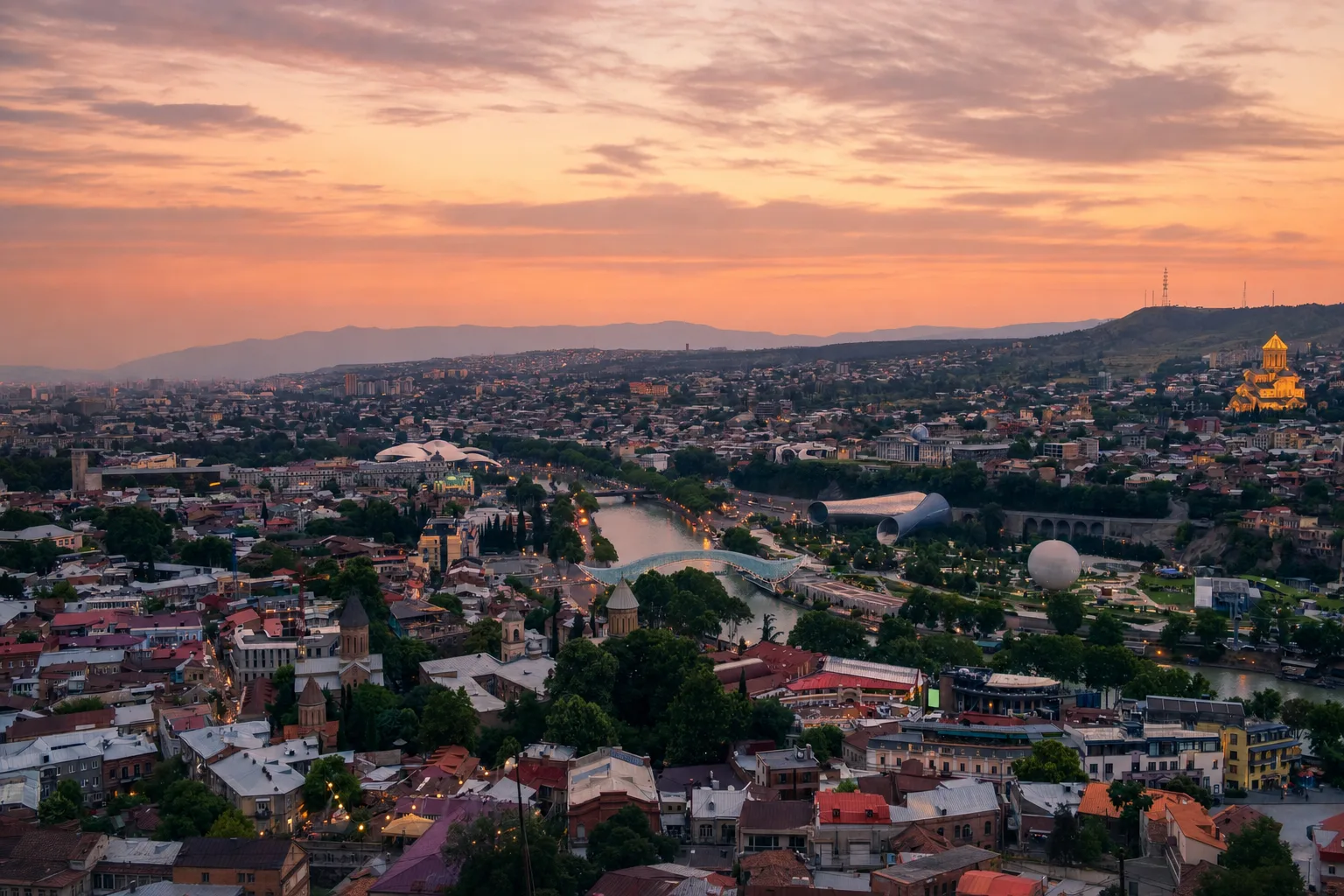 Old Tbilisi rooftops and the Mtkvari river at dusk with the Narikala fortress above