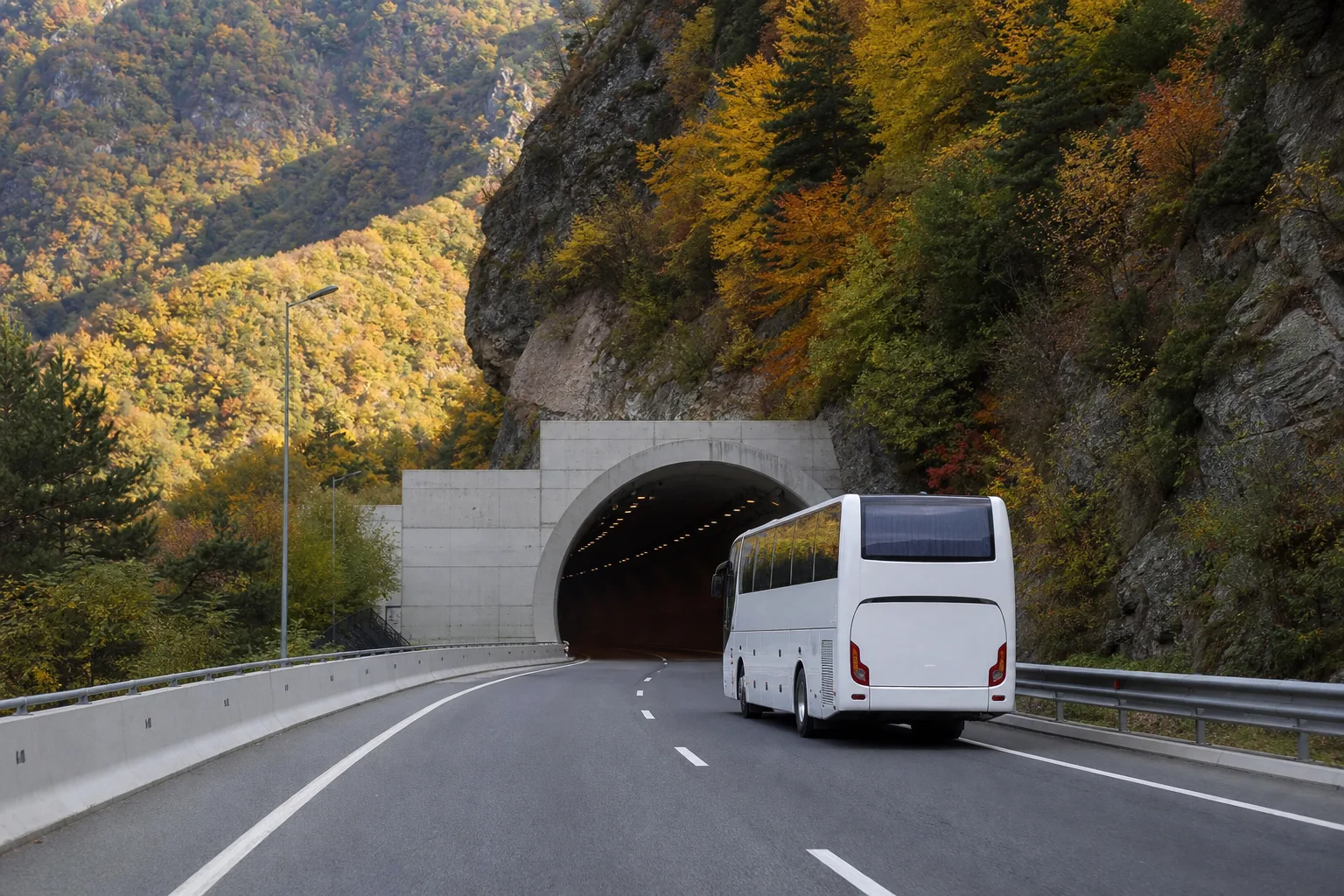 White intercity coach entering a tunnel portal on a new four-lane motorway through a wooded gorge in western Georgia