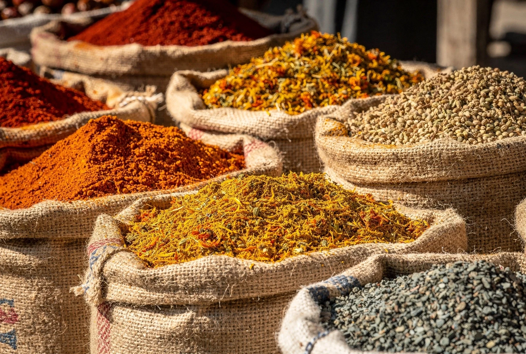 Colorful mounds of Georgian spices displayed in burlap sacks at a Tbilisi market