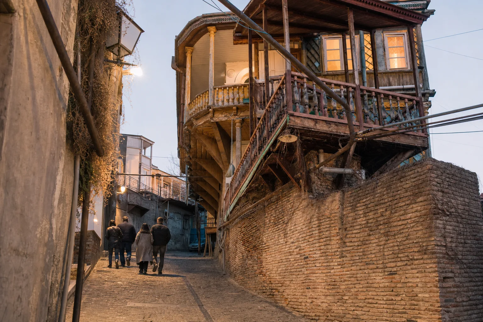 Golden hour view of Tbilisi Old Town streets with traditional wooden balconies and a hilltop fortress in the background